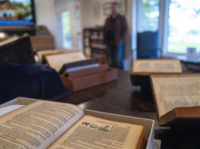 Open archival text with blurry person in background inside a reading room