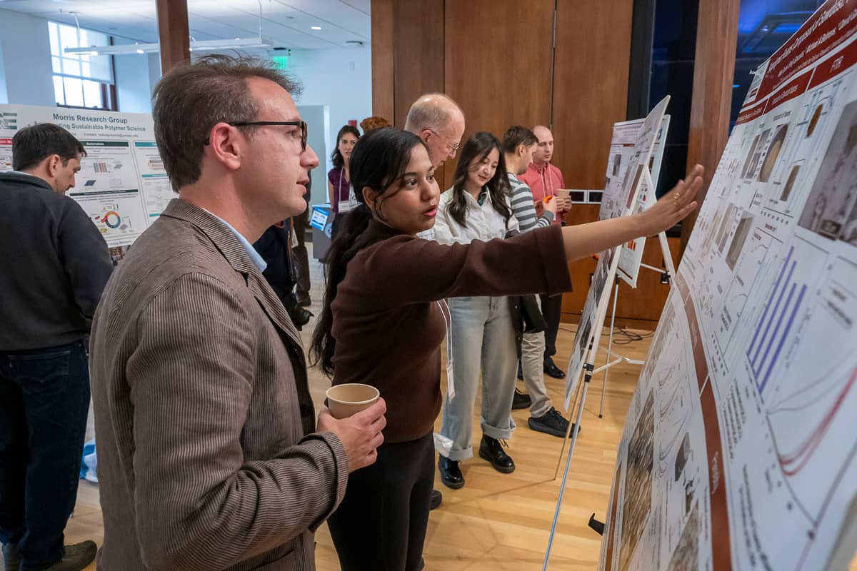 Scholars discussing a research poster